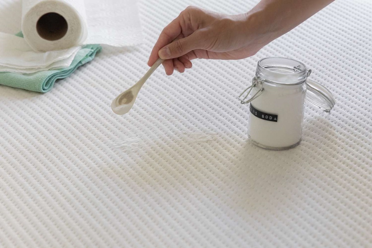 sprinkling baking soda on mattress to clean it